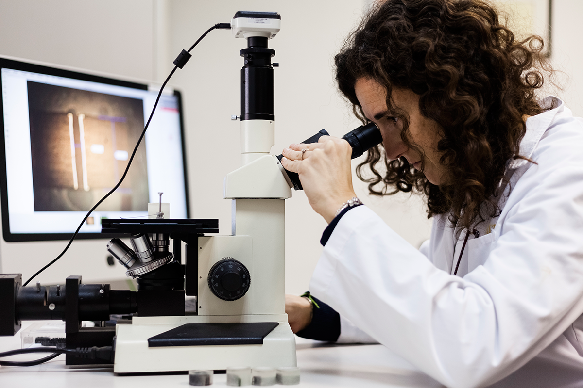 Trabajadora mirando a través de un microscopio